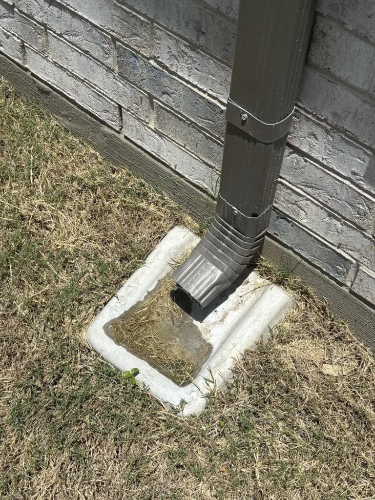 Downspout draining to a splash block during a Plano TX drainage and foundation inspection - Buffalo Property Inspections