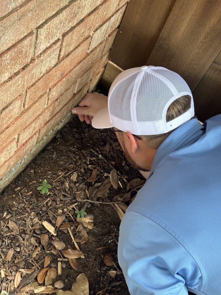 Home inspector checking foundation drainage and grading along a Dallas-Fort Worth home - Buffalo Property Inspections