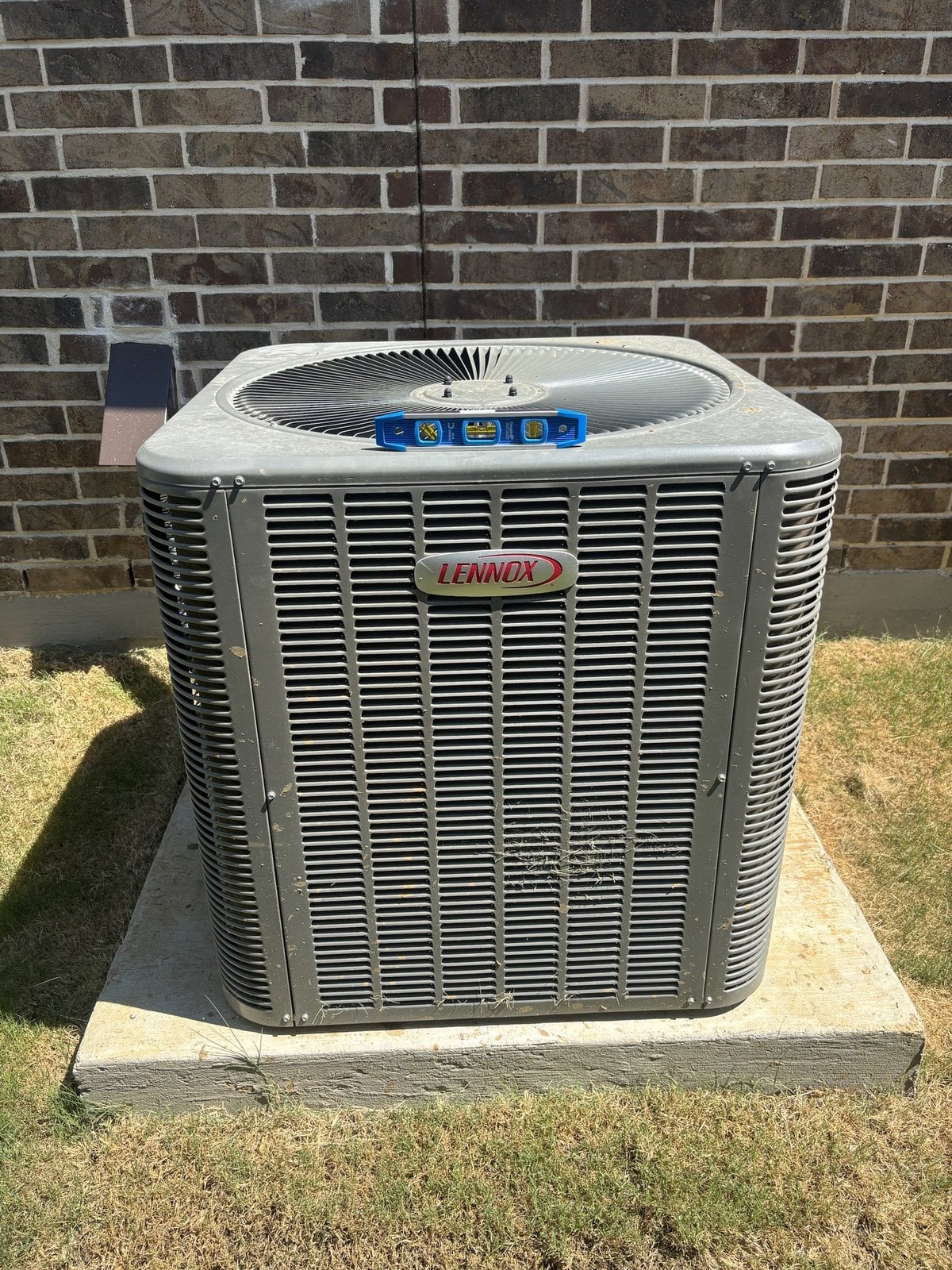 A home inspector checking an outdoor air conditioning condenser for level in Grapevine, Texas during a home inspection by Buffalo Property Inspections