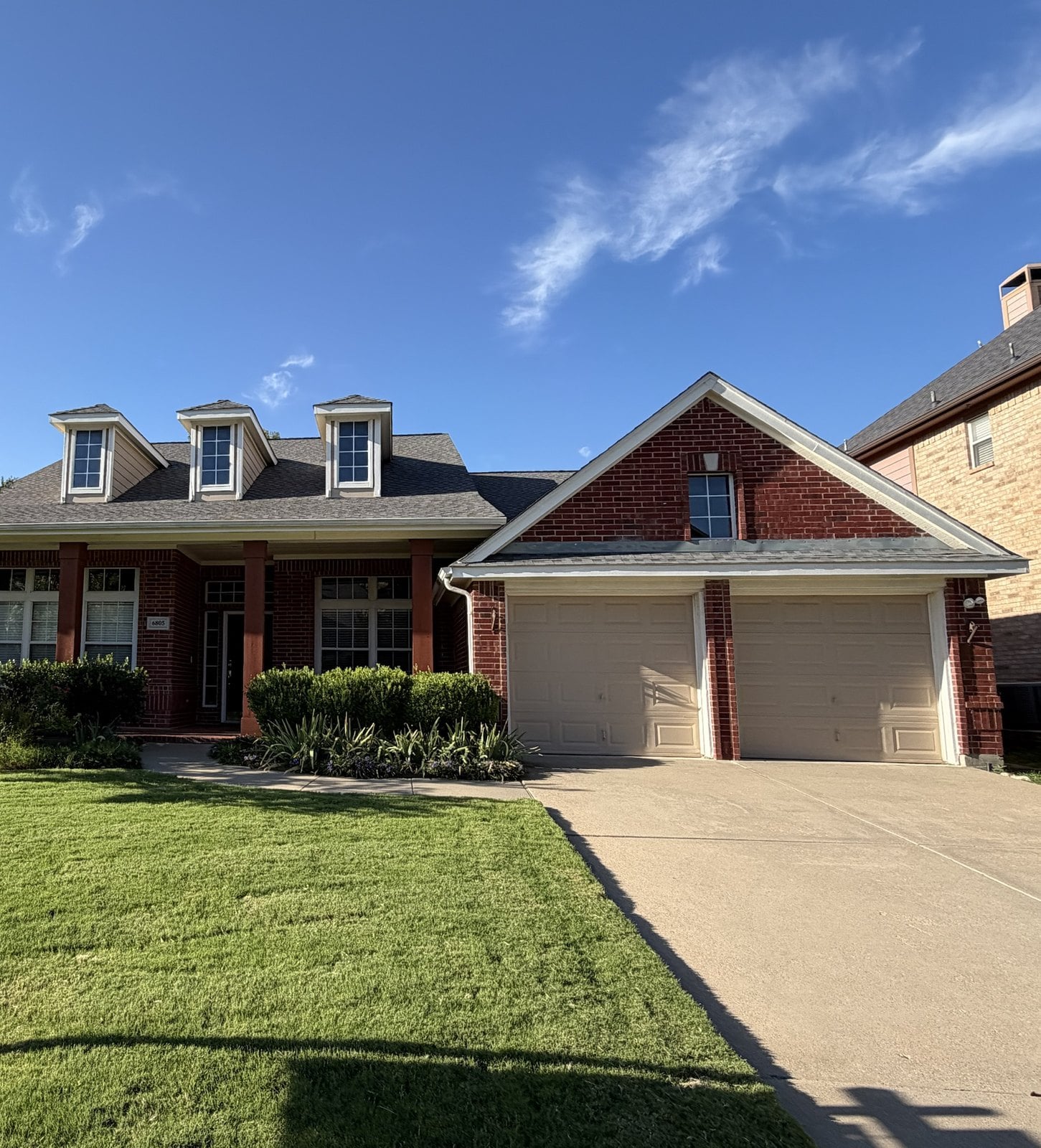 A two-story red brick home with dormer windows in Frisco, Texas during a home inspection by Buffalo Property Inspections