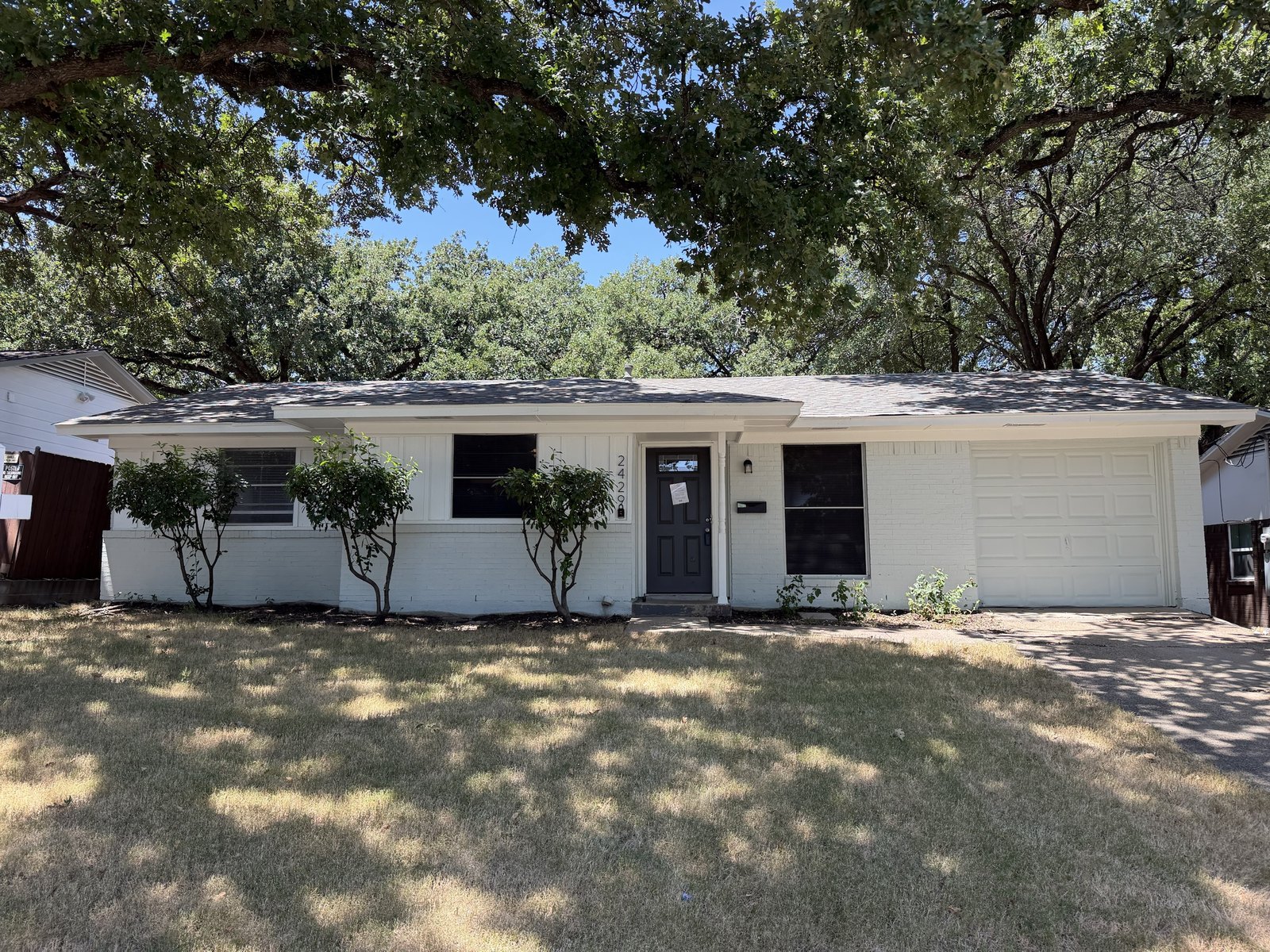 A white painted brick ranch home under mature oaks in McKinney, Texas during a home inspection by Buffalo Property Inspections